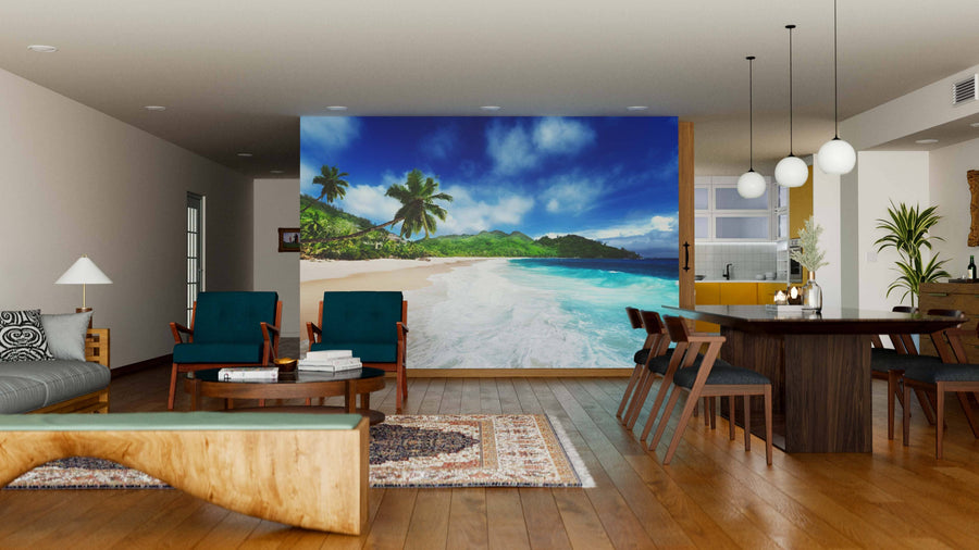 A modern living-dining room with wooden floors and stylish furniture features the Beach at Mahe Island Wall Mural, showcasing palm trees, blue sky, and ocean waves for an open, airy, and relaxing indoor atmosphere.