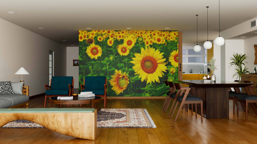 A modern open-plan living and dining area with wood floors and furniture features the Beautiful Sunflowers Wall Mural, a vibrant peel and stick design of blooming sunflowers on a green background that creates a cheerful focal point.