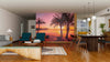A modern living and dining area with wooden floors features the Beautiful Tropical Beach Wall Mural, teal armchairs, a sofa, unique coffee table, rug, dining table with pendant lights, and a kitchen in the background.