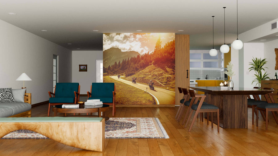 A modern open-concept living and dining room features wood floors, blue and wooden furniture, a patterned rug, and a large Bikers on Mountain Road Wall Mural. The kitchen can be seen in the background.