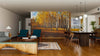 A modern living and dining room with wood floors, teal and wooden furniture, pendant lights, and a large Birch Tree Grove Wall Mural behind the dining area. The space feels open, inviting, and perfect for unique wall art.