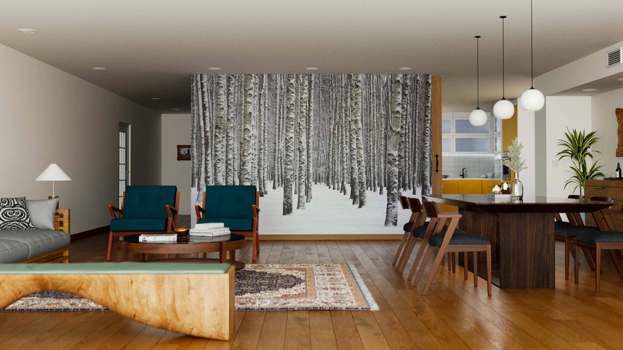 A modern living and dining area with wooden floors, teal and wooden furniture, patterned rugs, pendant lights, an open kitchen, plus a stunning Birch Trees In Winter Forest Wall Mural as a feature on one wall.