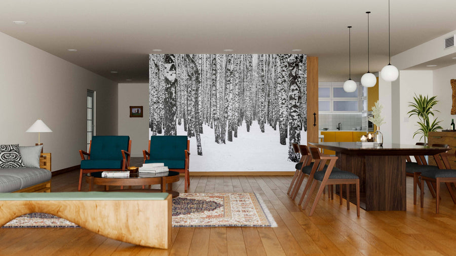 Modern living and dining area with wooden floors, mid-century furniture, cozy seating, dining table, globe pendant lights, natural light from windows, and a large Birch Trees In The Winter Wall Mural creating a wintry forest focal point.
