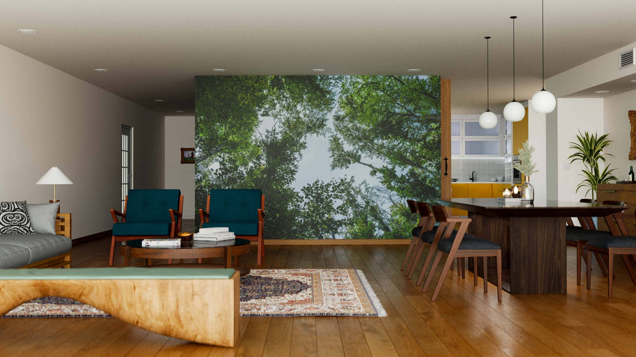 A modern open living-dining area with wood floors, mid-century furniture, and rugs features the Blue Sky Through Tree Branches Wall Mural. A six-seat dining table sits under globe lights, with the kitchen visible in the background.