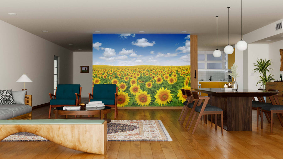 A modern living-dining room with wooden floors and furniture features the Blue Sky on a Sunflower Field Wall Mural, bringing vibrant color and nature-inspired charm to the cozy space with contemporary chairs and hanging lights.