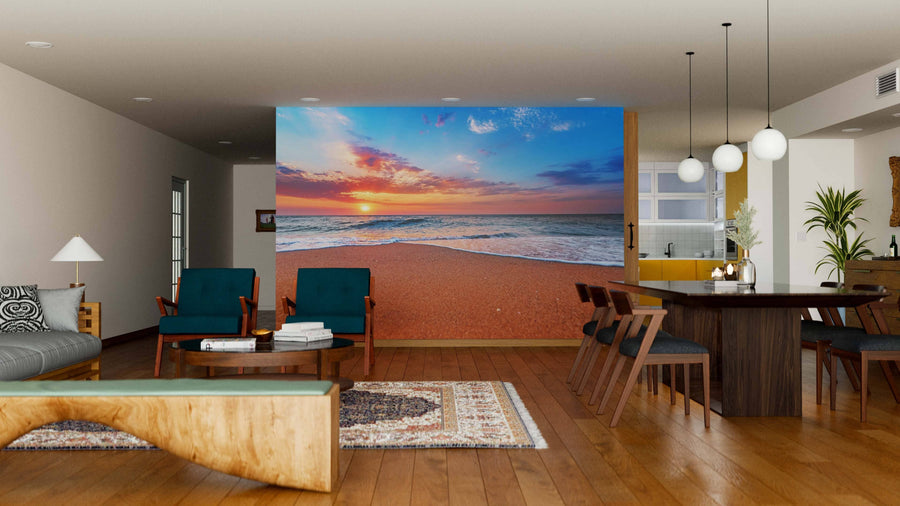 A modern living-dining room with wood floors and teal chairs features the Brilliant Ocean Beach Sunrise Wall Mural, a peel-and-stick design that adds vibrant color to the space. Warm lighting and rustic accents create a cozy, inviting atmosphere.