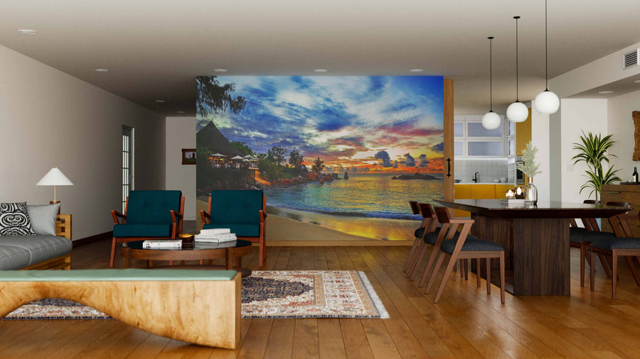 A modern living-dining room with wooden floors, green armchairs, a dark wood dining table, pendant lights, and the Cafe on Tropical Beach Wall Mural brings vibrant color and serenity to this contemporary interior.