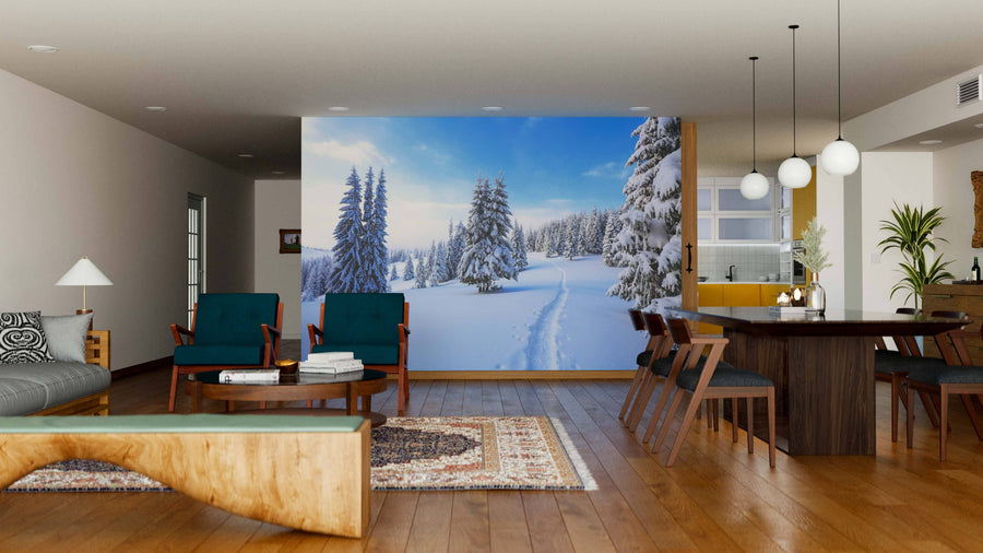 A modern open-plan living and dining room features wood floors, mid-century furniture, and a large Covered Winter Forest Wall Mural. Pendant lights hang over a dark dining table, with houseplants adding greenery.
