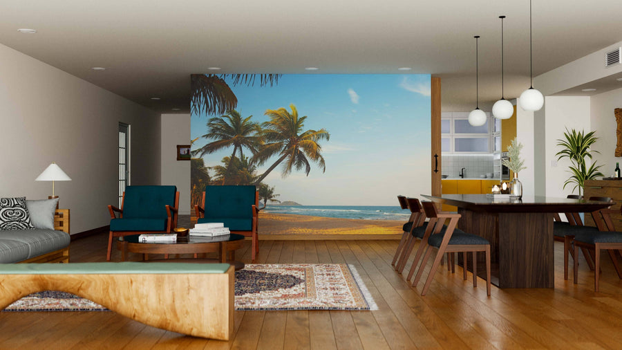 Modern living-dining area with wood flooring, teal armchairs, a unique wooden coffee table, and a large Exotic Lonely Beach Wall Mural. A long dining table with chairs and globe pendant lights are also visible.