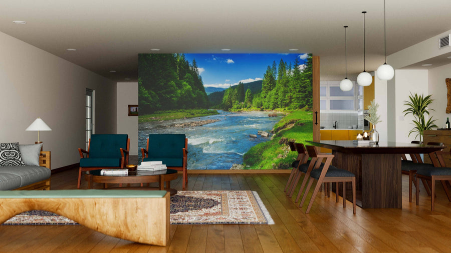 Modern living and dining room with wood floors, teal chairs, a large dining table, and the Fast Mountain River Wall Mural depicting a river through a forest under a blue sky, creating a serene natural vibe in the open-concept space.