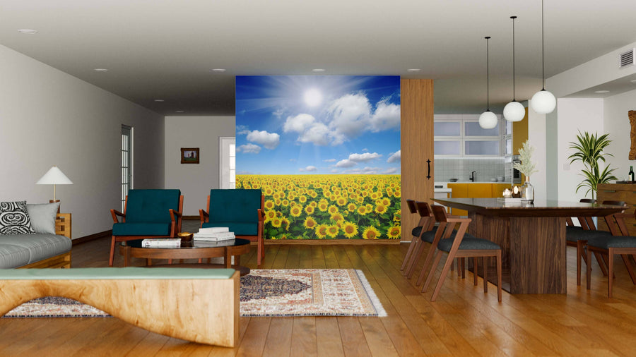 A modern open-plan living and dining area with wood floors and green chairs features the Field of Sunflowers Wall Mural, adding a sunny touch. Pendant lights illuminate the space, with a kitchen visible in the background.