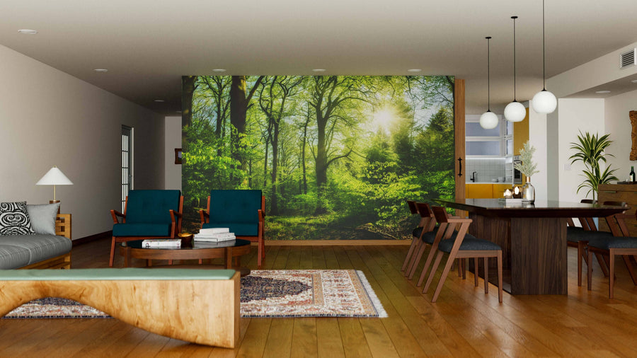 A modern living-dining room with wood floors, blue chairs, a gray sofa, and the Forest in Pleasing Sunlight Wall Mural. Pendant lights hang over a dark dining table for six, while natural accents add to the inviting, cozy atmosphere.