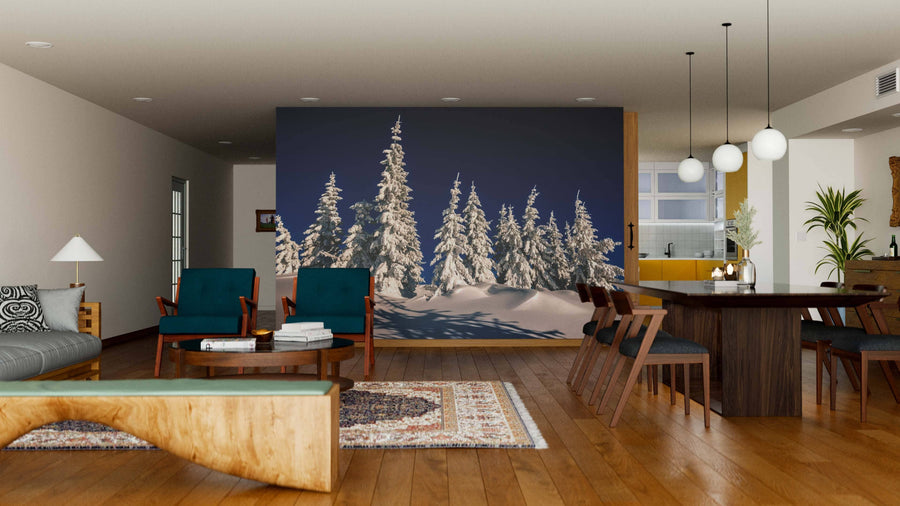 A modern living-dining room features wood floors, teal armchairs, a large dining table with six wooden chairs, and a Fragile Tree Covered in Frost Wall Mural. Warm lighting and contemporary decor create a cozy, stylish atmosphere.
