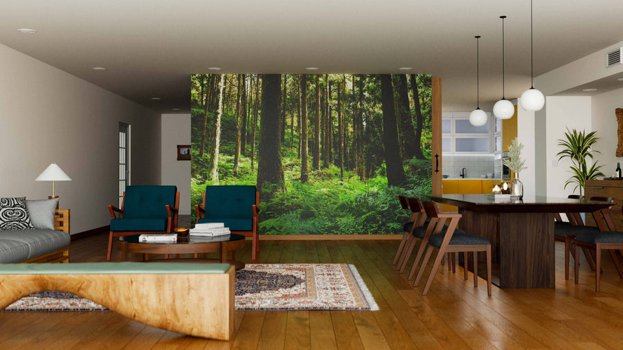 Modern living and dining room with wood floors, teal armchairs, a Green Forest of Alishan Wall Mural, dark wood dining table, pendant lights, rugs, and a kitchen in the background featuring yellow accents and white cabinetry.
