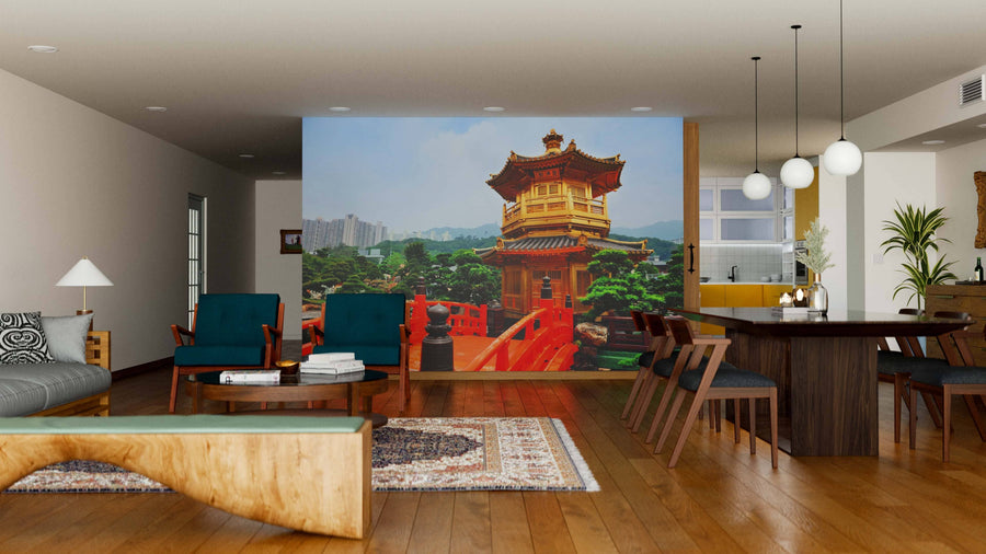 A modern living-dining room with wooden floors, teal armchairs, and a Hong Kong Garden Wall Mural depicting a traditional Asian pagoda, red bridge, and lush greenery. The dining area has a dark table, chairs, and globe pendant lights.
