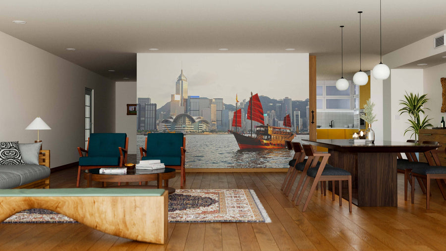 A modern living-dining room features wooden floors, mid-century furniture, and a Hong Kong Harbour Wall Mural with a red-sailed junk boat. Pendant lights illuminate the dining table, and rugs accentuate the seating areas.