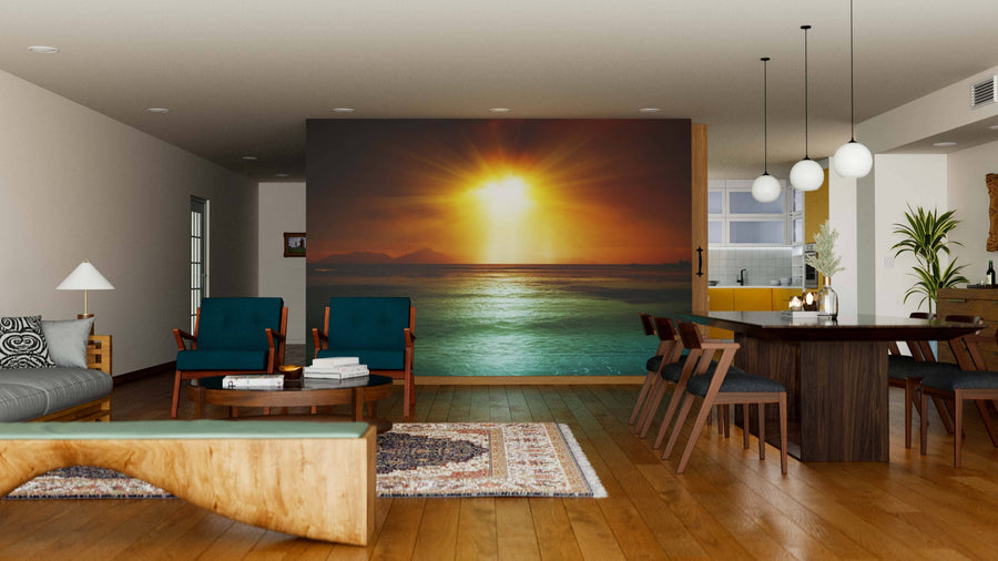 Modern living and dining room with wooden floors, teal armchairs, and a large La Digue Island, Seychelles Wall Mural depicting a sunset over the ocean. Pendant lights hang above the dark table; a rug and decor add warmth.