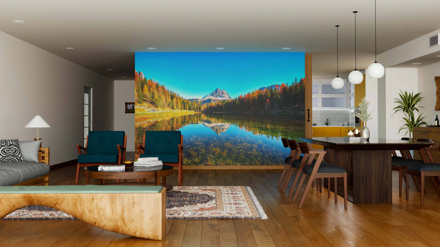 A modern living-dining room features wood floors, stylish furniture, and a striking Lake Antorno & Dolomite Peak Wall Mural. Pendant lights hang over the dining table while natural light streams in from the windows.