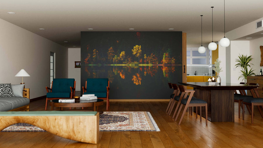 A modern open-concept living and dining room features wooden floors, mid-century furniture, pendant lights, a patterned rug, and the Lake Autumn Reflection Wall Mural—a peel and stick mural of illuminated trees reflected on water for a warm vibe.