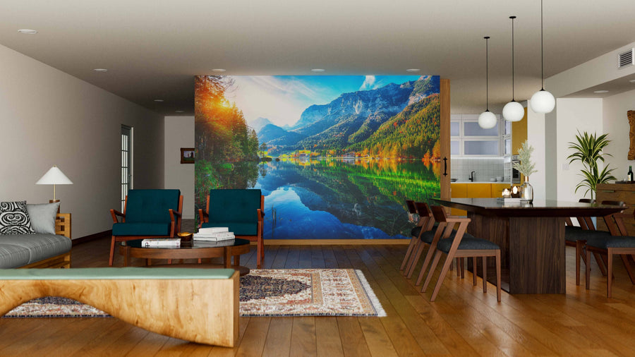 Modern living-dining room with wooden floors, teal armchairs, and a large Lake Hintersee and Reiter-Alm Wall Mural. Features a round dining table with chairs, pendant lights above, and an open kitchen visible in the background.