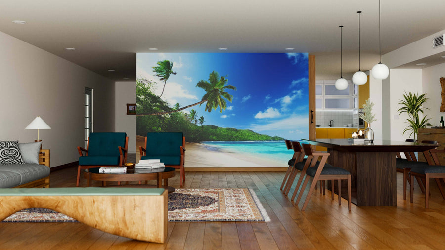 A modern living-dining room features wooden floors, teal chairs, and a patterned rug. The Mahe Island in Seychell Wall Mural with a tropical beach scene adds a vibrant, open feel to the space.