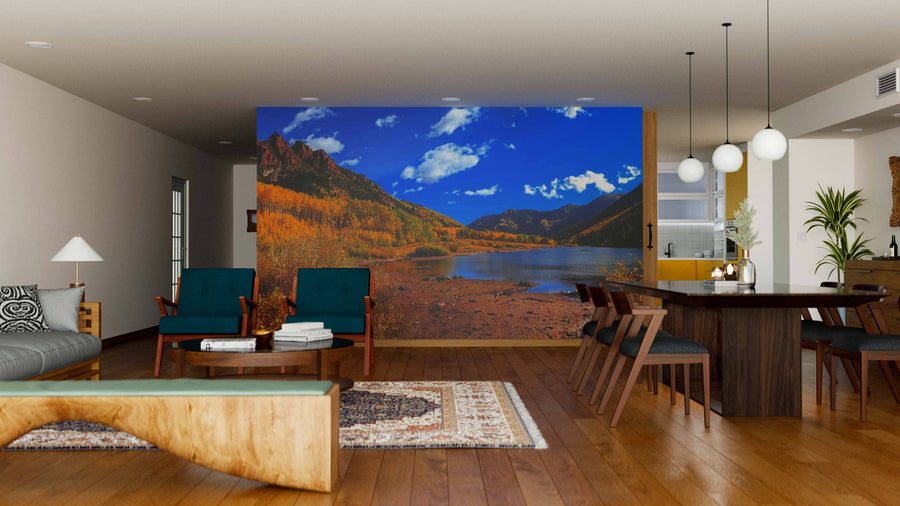 A modern living-dining room with wood floors and a large table features the Maroon Lake Panoramic View Wall Mural as a scenic focal point, adding vibrant color and easy-to-update style to the open space.