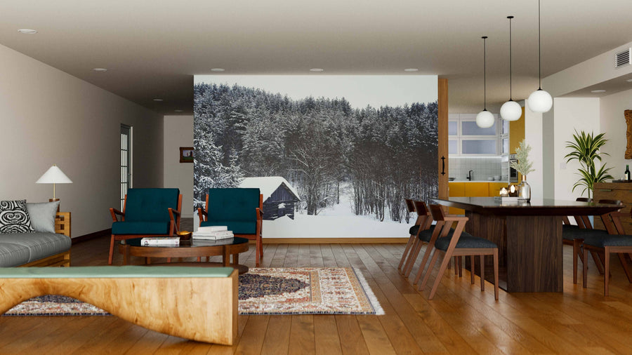 A modern living-dining room with wooden floors, teal and wood furniture, and the Old Log Cabin in Winter Wall Mural. Pendant lights, cozy rugs, a dining table, and plants create a warm, inviting atmosphere.