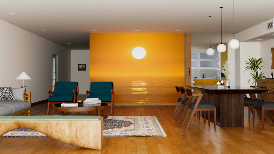 A modern living-dining room features wooden floors, teal chairs, a gray sofa, and a dining table. The Orange Sunset Wall Mural creates a warm focal point, enhanced by pendant lights and cozy plants.