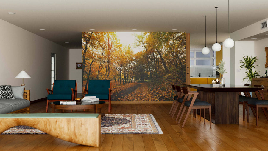 A modern living-dining room with wooden floors, blue armchairs, a brown dining table, and the Pathway in Autumn Park Wall Mural. Pendant lights and layered decor add warmth to this cozy space.