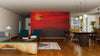 A modern living-dining room with wood floors, teal armchairs, and a large dining table. A bold red accent wall displays the Pier in Orlowo Wall Mural, bringing vibrant color and character to the neutral-toned space.