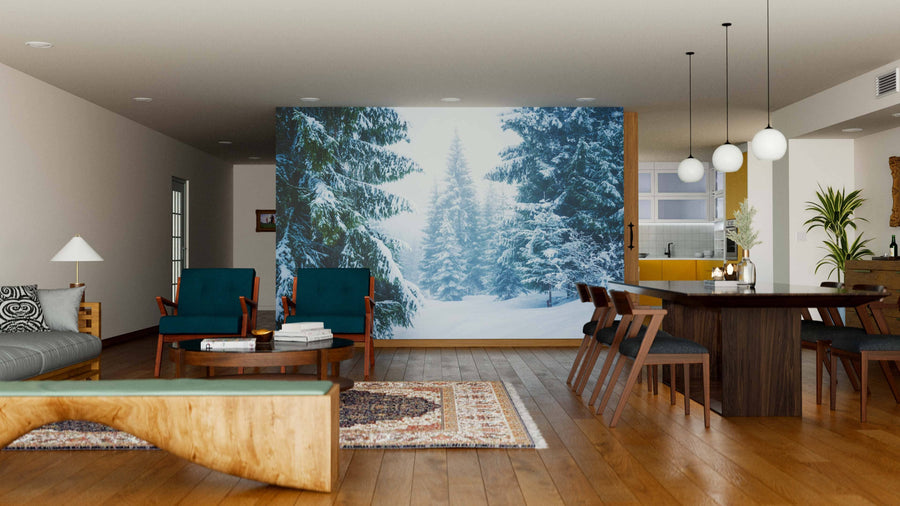 A modern living and dining area with wooden floors, teal chairs, and the "Pine Trees Covered by Snow Wall Mural." A patterned rug, round coffee table, contemporary dining table, and white globe lights complete this cozy space.