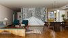 Modern living and dining room with wooden floors and furniture, featuring the 'Railway in the Winter Wall Mural,' a peel and stick mural depicting a snowy forest path lined with leafless trees that adds depth against the warm interior tones.
