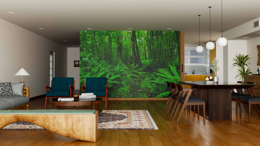 A modern living-dining space with wooden floors, mid-century furniture, and pendant lights features the Rainforest Fern Path Wall Mural as a lush green focal point, beautifully dividing the living area from the kitchen.
