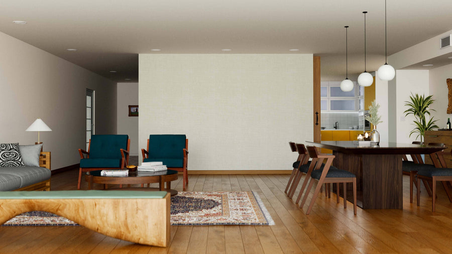 A modern living and dining room with wood floors, green armchairs, a gray sofa, a round coffee table, the Soft Weave Wall Mural, a wooden dining table for six, pendant lights above, rugs, plants, and a partially visible kitchen in the background.