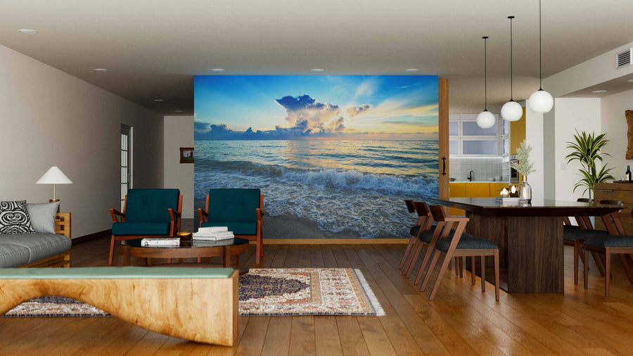 Modern living-dining room with wooden floors, dark green chairs, wooden table and globe lights features a large Sea Beach with Sunset Wall Mural that adds a stunning natural touch to the contemporary interior design.