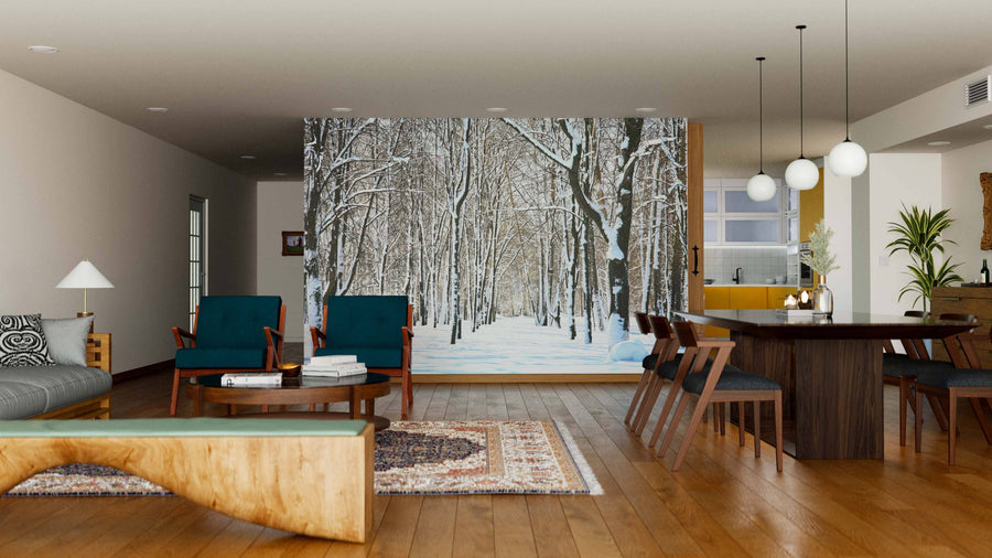A modern living-dining room with wooden floors, teal chairs, and a large table features the Snow on Trees in April Wall Mural, a peel and stick mural that brings a stylish wintry forest scene indoors with ease.