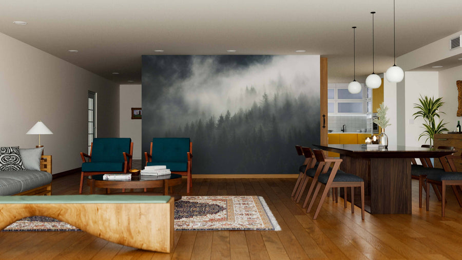 A modern open-plan living and dining area with wooden floors, teal chairs, and a dining table features the South Tyrol Misty Forest Wall Mural. Pendant lights hang overhead, and the kitchen is visible in the background.
