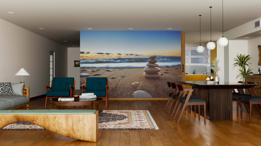 A modern dining and living area with wooden floors and furniture features the Stones Balanced on the Shore Wall Mural, blue chairs, a unique wooden bench, rugs, and globe lights suspended above the dining table.