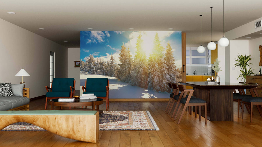 A cozy, modern living-dining room with wood floors and blue-toned furniture features the Stunning and Picturesque Winter Landscape Wall Mural, while spherical pendant lights above a dark dining table bring warmth to the inviting space.