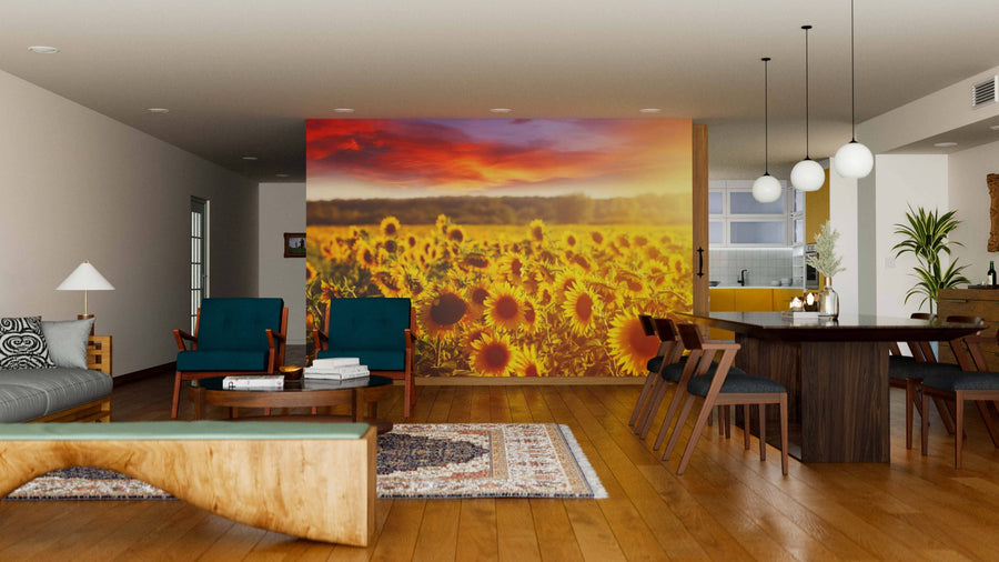 Modern open-plan living and dining room with wooden floors, stylish furniture, and a large Summer Sunflower Field Wall Mural as a vibrant divider at sunset. Spherical pendant lights hang above the dining table, creating a cozy atmosphere.
