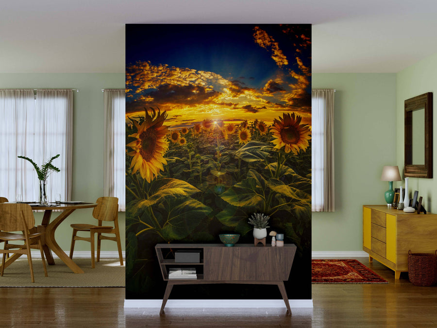 A modern living room with light green walls showcases the "Sunflower Field on Fisheye Lens Wall Mural" on the main wall, complemented by a wooden dining set, sideboard with decor, red rug, houseplants, and large windows with sheer curtains.