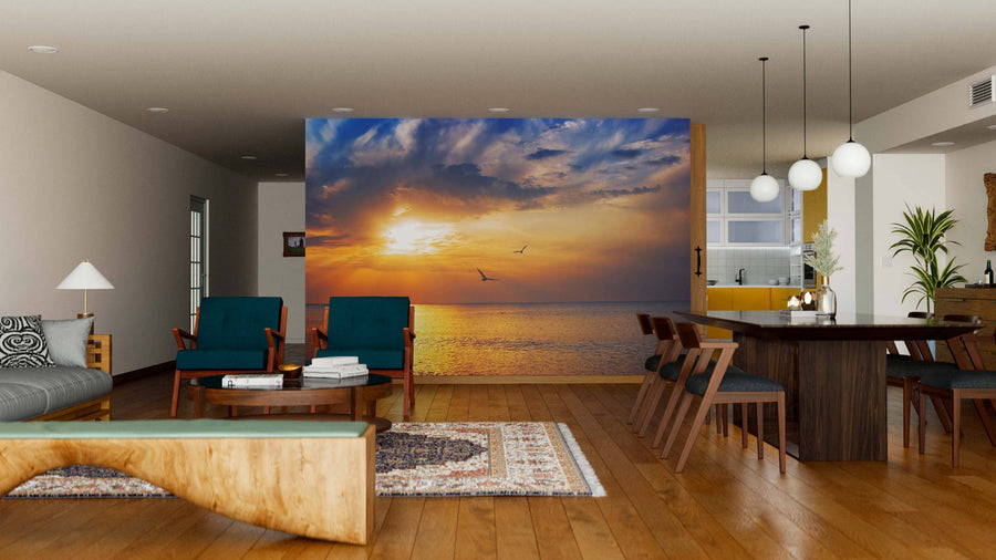 A modern living-dining room with wooden floors and furniture features a Sunrise at Sea Wall Mural on the back wall, adding a serene and artistic touch to this cozy, contemporary space.