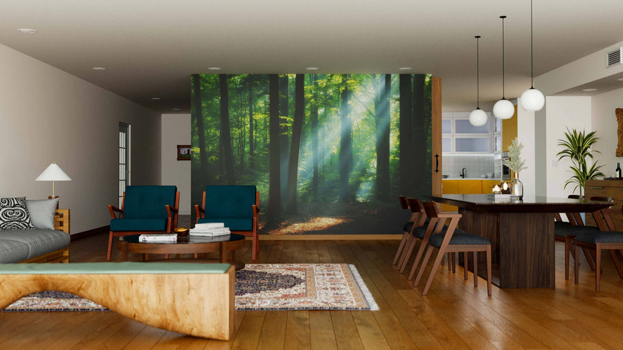 A modern living-dining room with wooden floors and cozy seating showcases the Sunrise in Green Forest Wall Mural, featuring sunrays through green trees. Rugs and pendant lights enhance the inviting space, perfect for removable wallpaper designs.