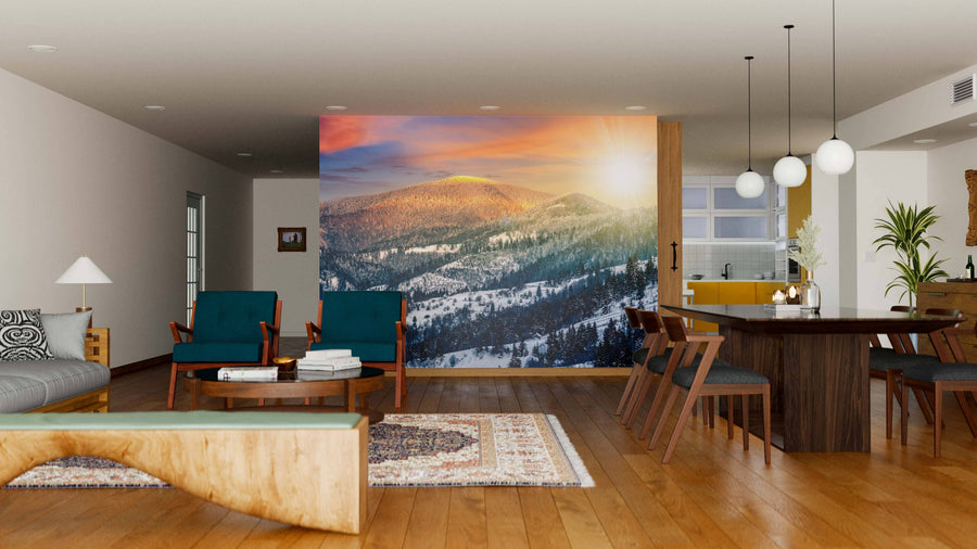 A modern open-plan living and dining room with wooden floors, stylish furniture, and the "Sunset in Winter Carpathians Wall Mural," showcasing a sunlit snowy mountain landscape that adds warmth and depth to the cozy, elegant space.