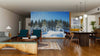 A modern living-dining area with wood floors, stylish furniture, and globe pendant lights features the Sunset in the Winter Forest Wall Mural, adding charm and a wintry landscape to this open, cozy space filled with natural and artificial light.
