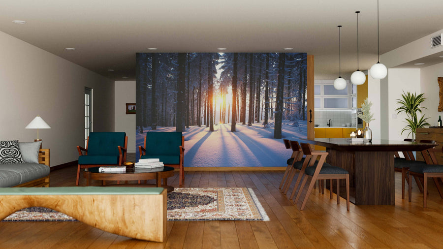 A modern living-dining room features wood floors, mid-century furniture, and the "Sunset in the Woods in Winter Wall Mural," bringing natural warmth and sunlight to the stylish interior with its snowy forest scene.