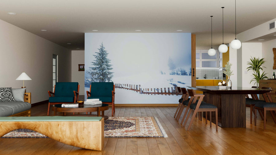 A modern living-dining room features blue armchairs, a wood coffee table, a dining set, and the Tall Slender Snowy Fir Trees Wall Mural. Wooden floors, rugs, pendant lights, and green plants complete the cozy, open space.
