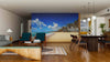 A modern open-plan living and dining room with wooden floors, teal chairs, and a large table is brightened by the Tropical Exotic Beach Wall Mural, which creates a relaxing tropical atmosphere.
