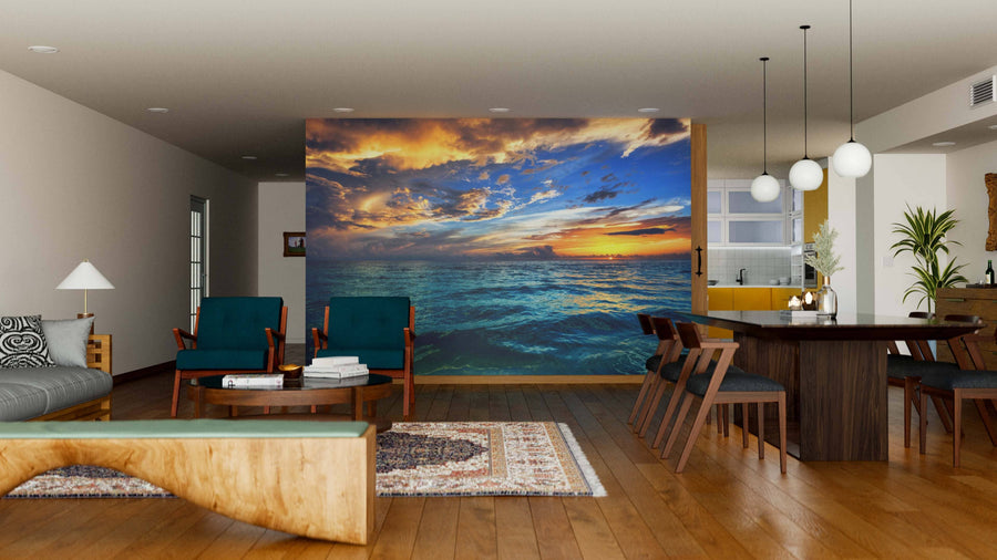 A modern open-plan living and dining room with wooden floors, mid-century furniture, pendant lights, rugs, and a Tropical Ocean Sunset Wall Mural adds vibrant color and depth to the neutral-toned space.