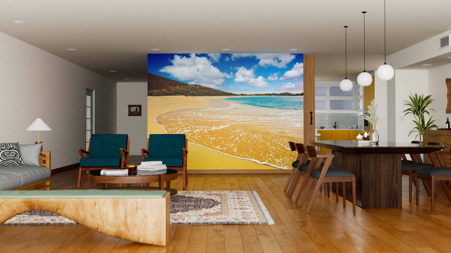 A modern living-dining room with wooden floors, stylish seating, a dining table, and globe pendant lights is brightened by the Tropical Paradise Wall Mural, featuring a sandy beach and blue ocean for a vibrant tropical flair.